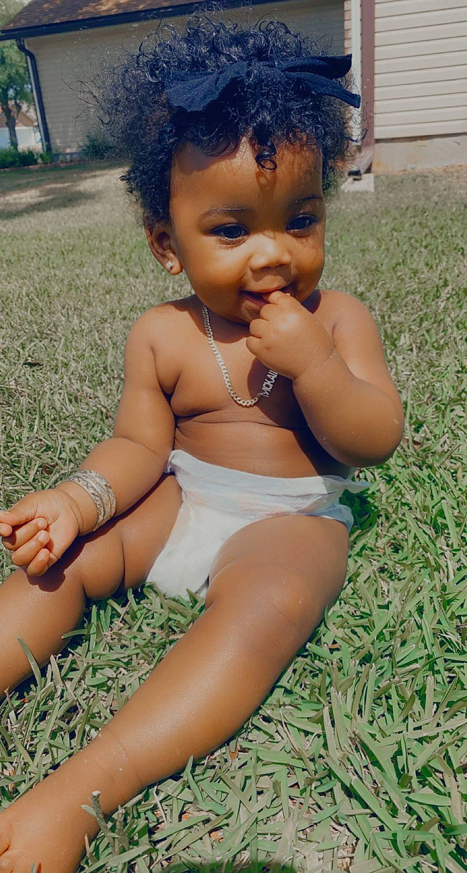 Mckailyn is registered to the contest to win money with this photo: abdomen, afro, black_hair, chest, eye, face, grass, hair, happy, head, knee, leg, person, plant, skin, smile, thigh, thumb, toddler, trunk