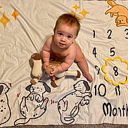 Sebastian joined the competition — help win amazing prizes! baby, child, blanket, carpet, knitted_toy, stuffed_animal, dog_illustration, numbers, months_marker, cute, indoor, floor, playtime, infant, smiling, looking_up, skin, hair, sitting, curious