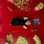 baby, black_clothing, celebration, clapperboard, coca_cola, cute, food_spill, fun, infant, lying_down, movie_theme, popcorn, popcorn_box, question_mark_shape, red_background, small_cans, soft_toy, still_life, studio_shot, white_shirt