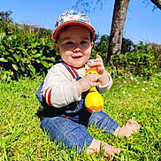 Gabriel participe au concours pour gagner de l'argent avec cette photo : baby, barefoot, blue_sky, cap, child, cute, daylight, denim_overalls, grass, greenery, infant, nature, outdoor, playful, portrait, sitting, smile, sunny, toy, tree