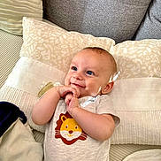Gaspard a rejoint le concours — aidez-le/la à gagner de superbes lots ! baby, infant, cute, smile, onesie, lion_print, pillow, couch, cozy, happy, child, indoor, clothing, hands, face, blue_eyes, light, pattern, soft, relaxing