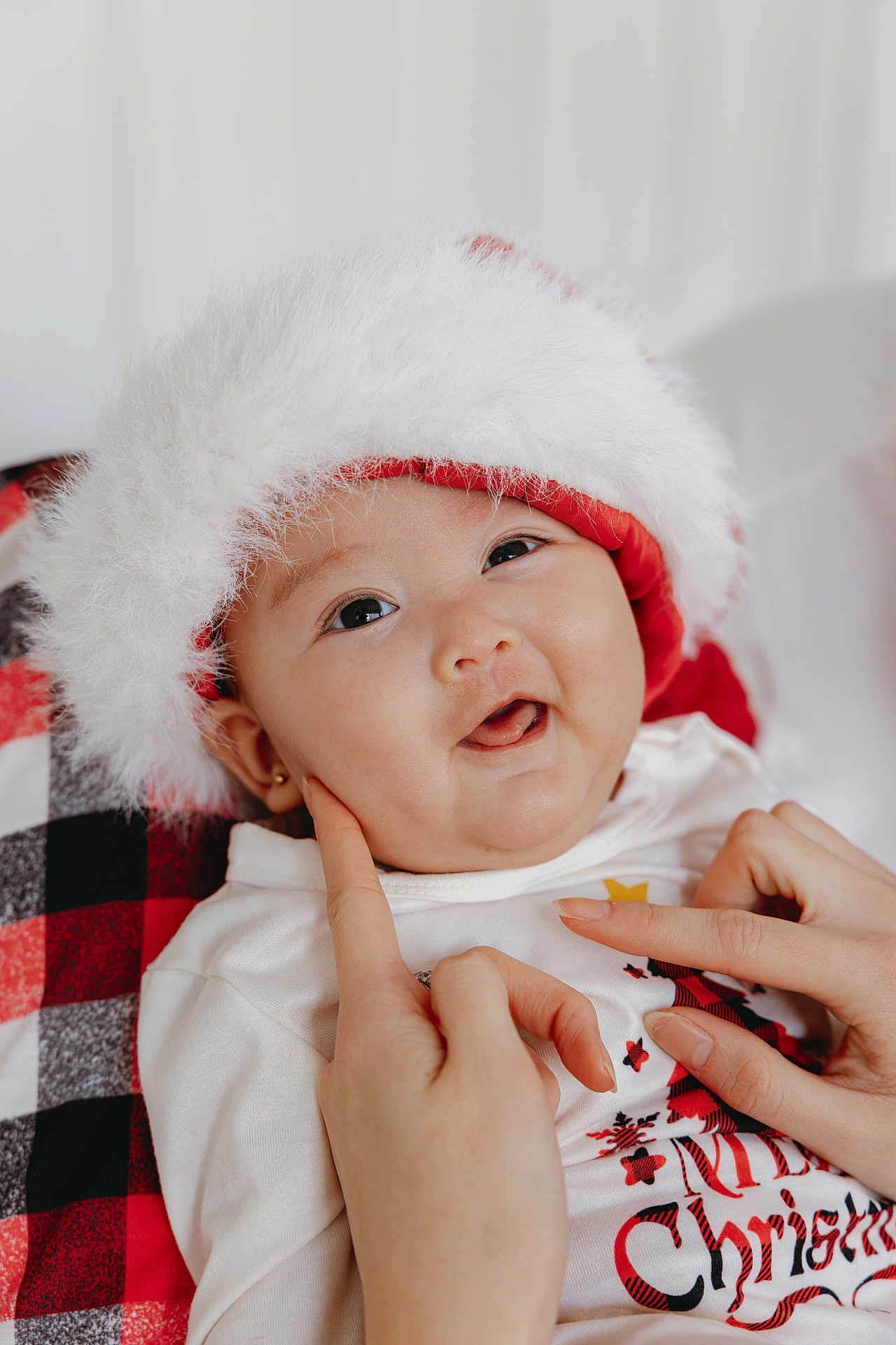 Arlina is registered to the contest to win money with this photo: baby, child, face, hands, smile, christmas, santa_hat, white_clothing, plaid_blanket, festive, holiday, cute, infant, portrait, happy, skin, fingers, cozy, warm, celebration