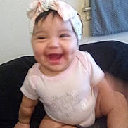 Luna joined the competition — help win amazing prizes! baby, child, smiling, headband, pink_socks, sitting, indoor, cute, happy, infant, clothing, face, person, floor, sock, hand, leg, toddler, blurred, joyful