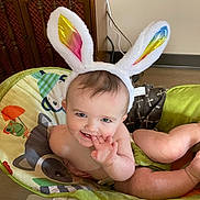 Emory joined the competition — help win amazing prizes! baby, bunny_ears, baby_seat, smiling, child, indoor, blanket, wooden_furniture, playful, cute, infant, face, hand, legs, colorful, comfort, home, person, cheerful, soft