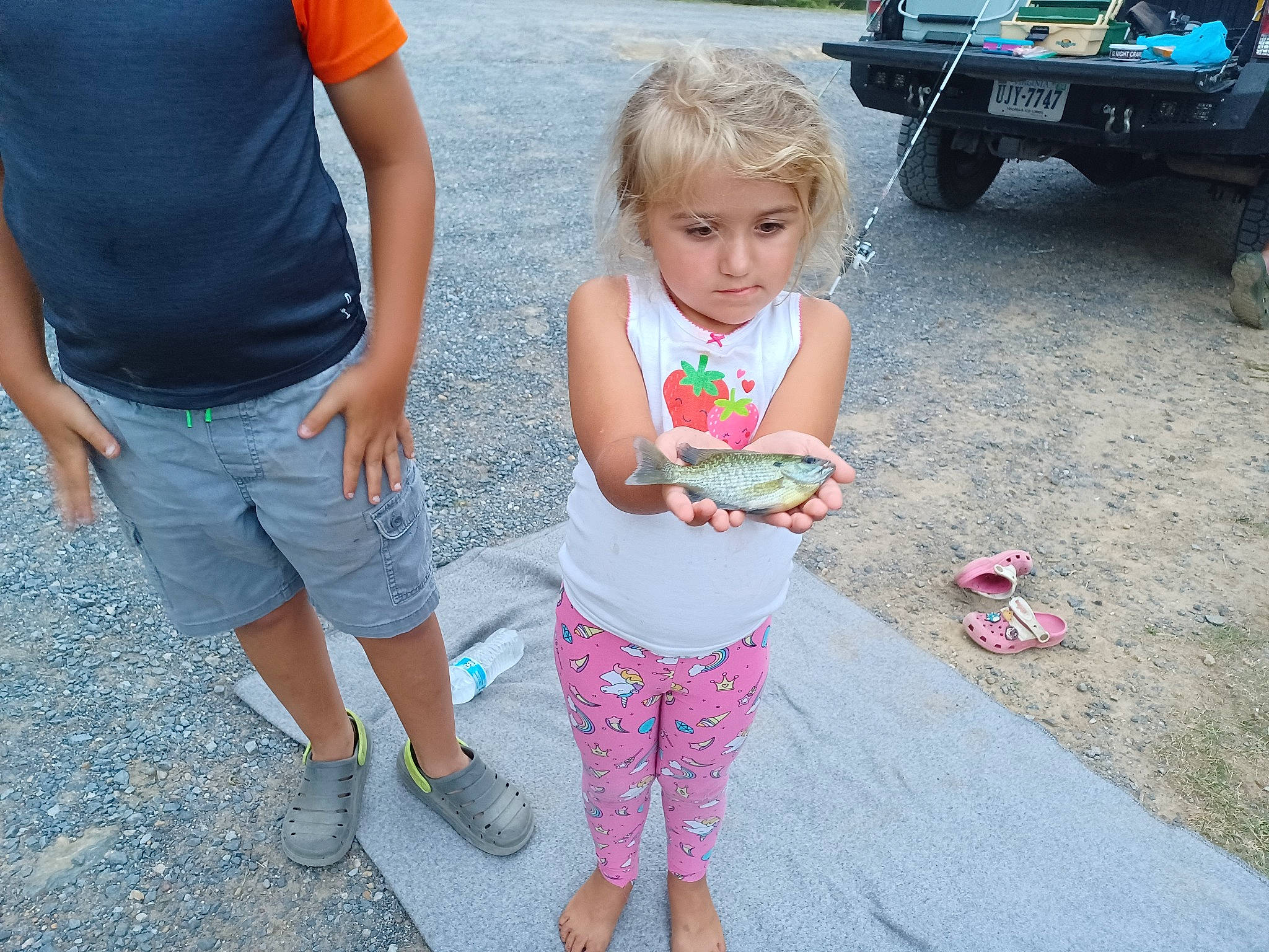 Daisie is registered to the contest to win money with this photo: asphalt, event, fun, gesture, grass, joint, leg, leisure, motor_vehicle, person, pink, public_space, recreation, shorts, sidewalk, thigh, tire, toddler, tree, vertebrate