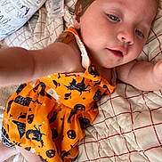 Liliana Rose joined the competition — help win amazing prizes! toddler, child, baby, orange_dress, halloween, bed, quilt, blanket, portrait, cute, indoor, person, face, expression, clothing, smile, reaching_hand, skin, hair, lying_down