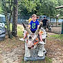 animals, blue_shirt, boy, child, daytime, dinosaur, fence, fun, grass, nature, outdoor, park, people, playground, recreation, statue, summer, trees, triceratops, white_shoes