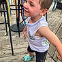 child, boy, smiling, outdoor, playground, wooden_deck, sleeveless_shirt, shorts, colorful_shoes, happy, person, daylight, casual_clothing, active, cute, fun, summer, playful, young, portrait