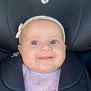 Melly a rejoint le concours — aidez-le/la à gagner de superbes lots ! baby, child, smiling, headband, bow, car_seat, black, pink, clothing, face, portrait, infant, cute, happy, seatbelt, young, closeup, person, indoors, soft
