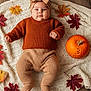 baby, infant, knitted_clothing, headband, autumn_leaves, pumpkin, blanket, floor, fall, seasonal, orange, brown, cute, child, portrait, indoors, laying_down, warm_clothing, decor, holiday