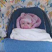 Lyla is registered to the contest to win money with this photo: baby, stroller, blanket, pacifier, hat, pink, blue, face, child, infant, canopy, patterned_fabric, animal_ears, wrapped, cozy, outdoor, cute, portrait, young_child, warm