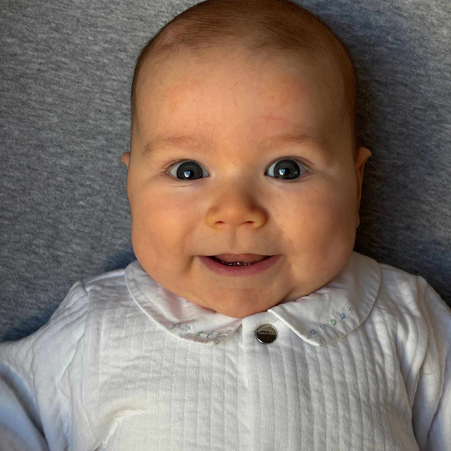 Djéo a rejoint le concours — aidez-le/la à gagner de superbes lots ! baby, button, cheeks, child, closeup, collar, cute, eyes, face, happy, head, indoors, infant, lying_down, person, portrait, skin, smile, soft_background, white_clothing