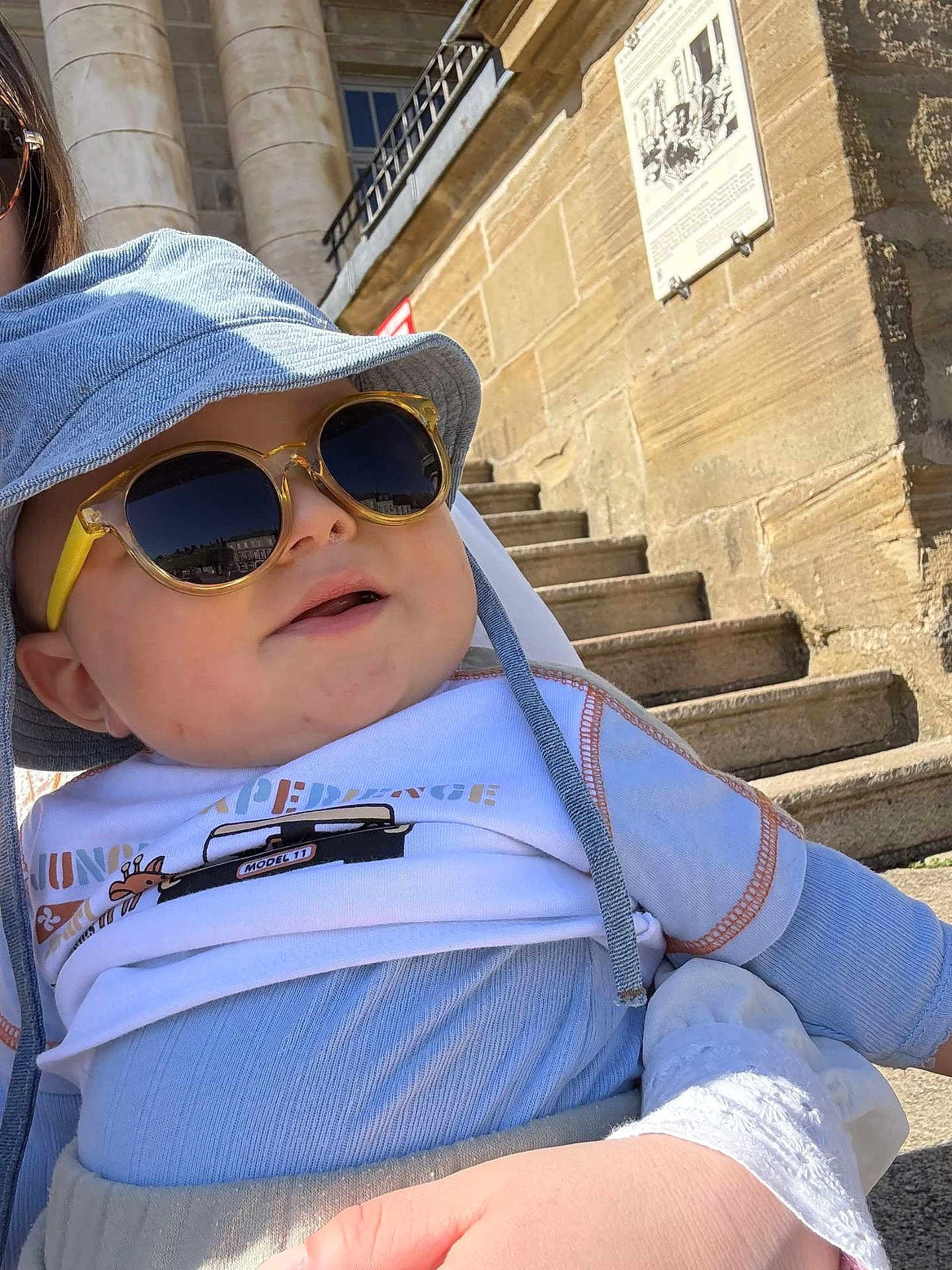 Adélio a rejoint le concours — aidez-le/la à gagner de superbes lots ! baby, child, sunglasses, hat, outdoor, stairs, building, stone, person, blue_clothing, white_clothing, sunny, daylight, casual, fashion, cool, accessory, cute, holding, portrait