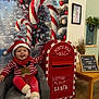 toddler, child, christmas, holiday, festive, santa_hat, reindeer_sweater, candy_cane, mailbox, north_pole_mail, chair, smiling, indoor, decorations, table, sign, wooden_floor, happy, seasonal, celebration