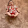 Elyna participe au concours pour gagner de l'argent avec cette photo : baby, child, smiling, happy, face, infant, red_clothing, patterned_shirt, cherry_pattern, carpet, floor, barefoot, nail_polish, toes, indoor, person, cute, lying_down, plush_texture, skin
