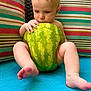 Derek is registered to the contest to win money with this photo: baby, watermelon, child, sitting, colorful, cushion, striped, blue, foot, hand, skin, indoors, fruit, cute, expression, seat, playful, young, person, background