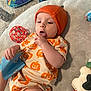 Derek joined the competition — help win amazing prizes! baby, infant, orange_hat, pumpkin_outfit, toy, playmat, plush_toy, red_ball, carpet, child, cute, indoor, soft_texture, knit_hat, exploring, tongue_out, casual_clothing, relaxing, young_child, playtime