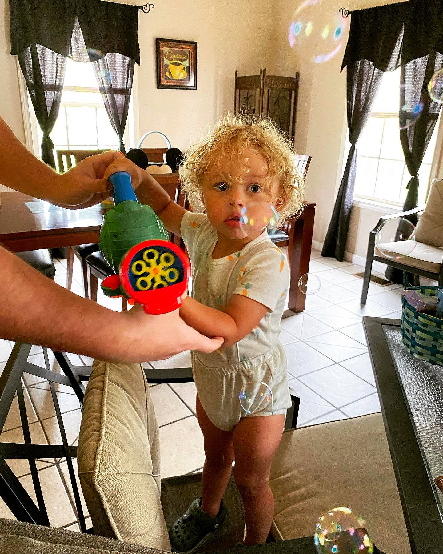 Jasiah is registered to the contest to win money with this photo: child, curtain, flooring, fun, gesture, happy, human_leg, lamp, leg, leisure, person, picture_frame, play, refrigerator, room, shorts, standing, thigh, thumb, toddler