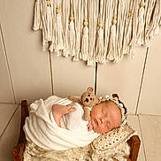 Maya joined the competition — help win amazing prizes! newborn, baby, sleeping, blanket, wooden_bed, crocheted_toy, headband, macrame, tassels, pillow, wool, knitting, soft_texture, cozy, indoors, portrait, peaceful, infant, wrapped, cute