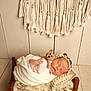 newborn, baby, sleeping, blanket, wooden_bed, crocheted_toy, headband, macrame, tassels, pillow, wool, knitting, soft_texture, cozy, indoors, portrait, peaceful, infant, wrapped, cute