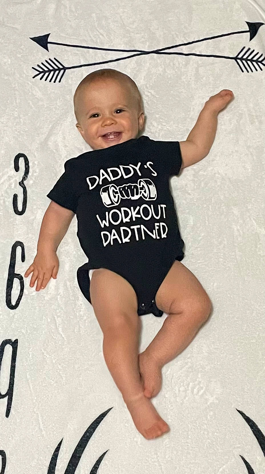 Charles is registered to the contest to win money with this photo: arm, baby_toddler_clothing, eye, face, finger, gesture, happy, head, human_body, joint, joy, leg, neck, one_piece_garment, person, sleeve, smile, standing, t_shirt, thigh