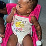 baby, child, onesie, pink_chair, pacifier, sitting, indoors, floor, bracelet, cute, clothing, infant, person, skin, hair, furniture, expression, hand, toy, accessory