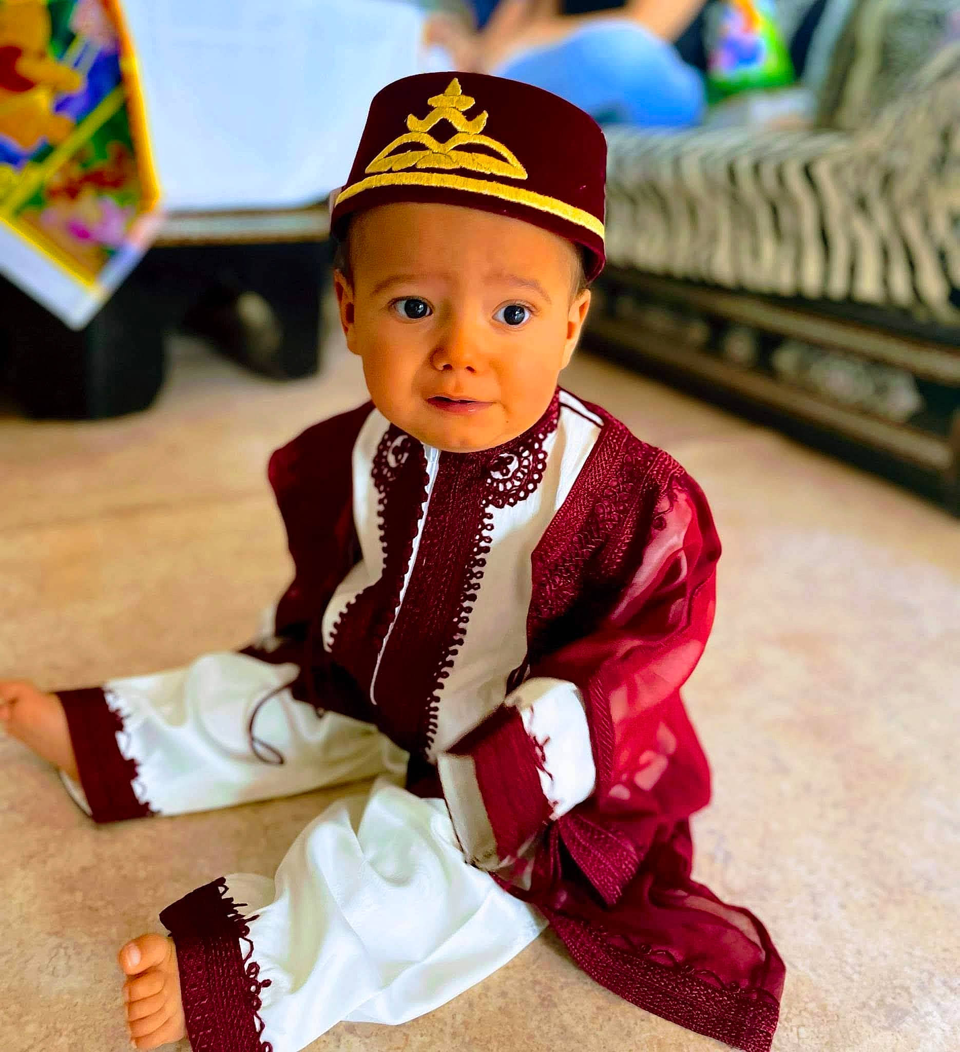 Sofiane a rejoint le concours — aidez-le/la à gagner de superbes lots ! baby, baby_toddler_clothing, cap, carmine, child, costume, costume_hat, electric_blue, fashion_accessory, flooring, formal_wear, fun, happy, pattern, person, play, sitting, sleeve, toddler, tradition