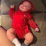 baby, infant, red_hoodie, couch, socks, smile, dimples, legs, arms, face, person, clothing, indoor, cute, happy, soft_lighting, casual, relaxed, cozy, child