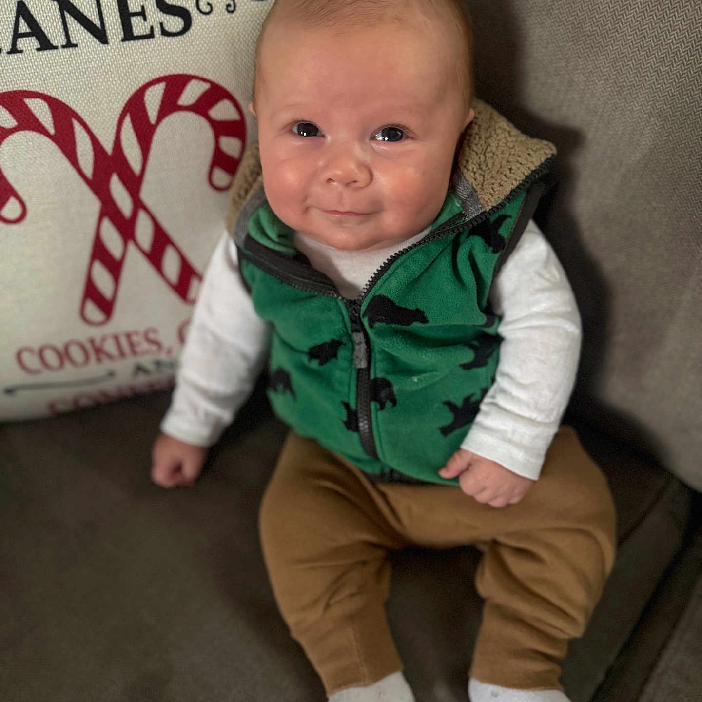 Colten joined the competition — help win amazing prizes! baby, brown_pants, candy_canes, child, clothing, couch, cozy, cute, face, green_vest, happy, holiday_pillow, home, indoor, infant, portrait, sitting, smiling, white_socks, young