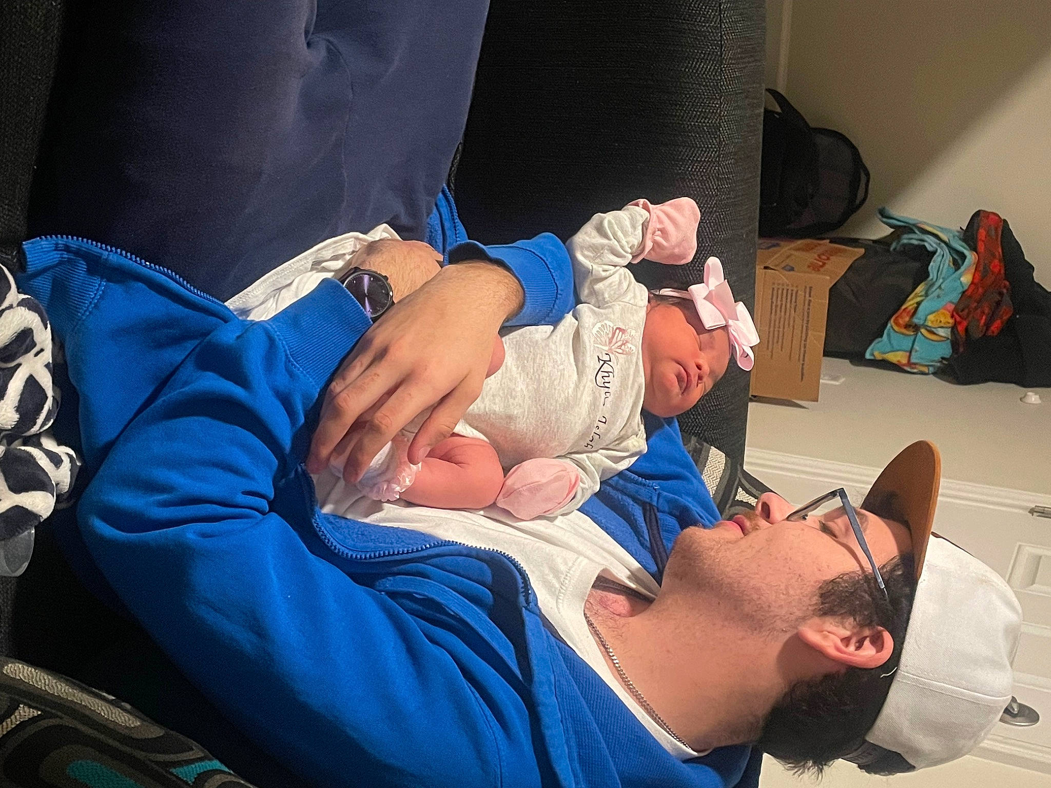 Khylie is registered to the contest to win money with this photo: abdomen, baby, child, comfort, couch, elbow, event, finger, fun, hat, headwear, health_care, human, joint, knee, medical_procedure, people, person, room, service