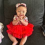 baby, child, tutu, red_dress, headband, smiling, couch, indoor, happy, cute, sitting, infant, clothing, portrait, feet, hands, face, person, fabric, home