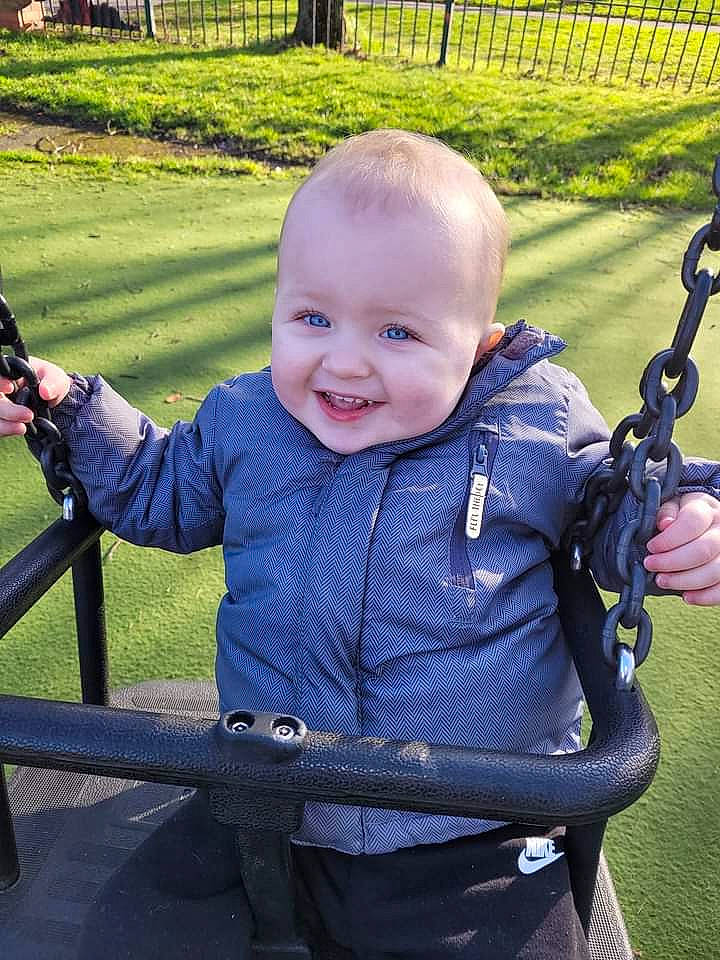 William is registered to the contest to win money with this photo: baby, baby_toddler_clothing, child, electric_blue, eye, facial_expression, fun, grass, green, happy, joy, leisure, people_in_nature, person, plant, public_space, recreation, skin, smile, standing