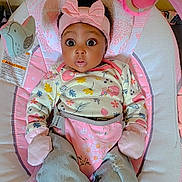 Journey is registered to the contest to win money with this photo: baby, infant, pink, headband, bow, onesie, denim_jeans, mittens, baby_bouncer, toy, floral_pattern, cute, wide_eyes, expression, indoor, child, person, soft_toys, seat, colorful