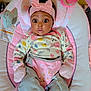 baby, infant, pink, headband, bow, onesie, denim_jeans, mittens, baby_bouncer, toy, floral_pattern, cute, wide_eyes, expression, indoor, child, person, soft_toys, seat, colorful