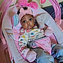 Journey is registered to the contest to win money with this photo: baby, infant, pink, mittens, baby_rocker, clothing, headband, toy, indoor, cute, child, seat, face, portrait, person, jeans, apparel, comfort, expression, baby_toys