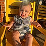 baby, child, yellow_chair, sunlight, striped_clothing, outdoor, cute, portrait, infant, smiling, sitting, summer, shadow, relaxing, playful, sunshine, skin, foot, hand, expression