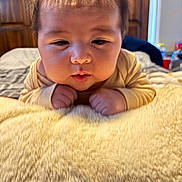 Michael joined the competition — help win amazing prizes! baby, infant, child, face, hair, blanket, bed, furniture, wood, room, indoor, curious, puckered_lips, hands, soft_texture, yellow, clothing, person, portrait, closeup