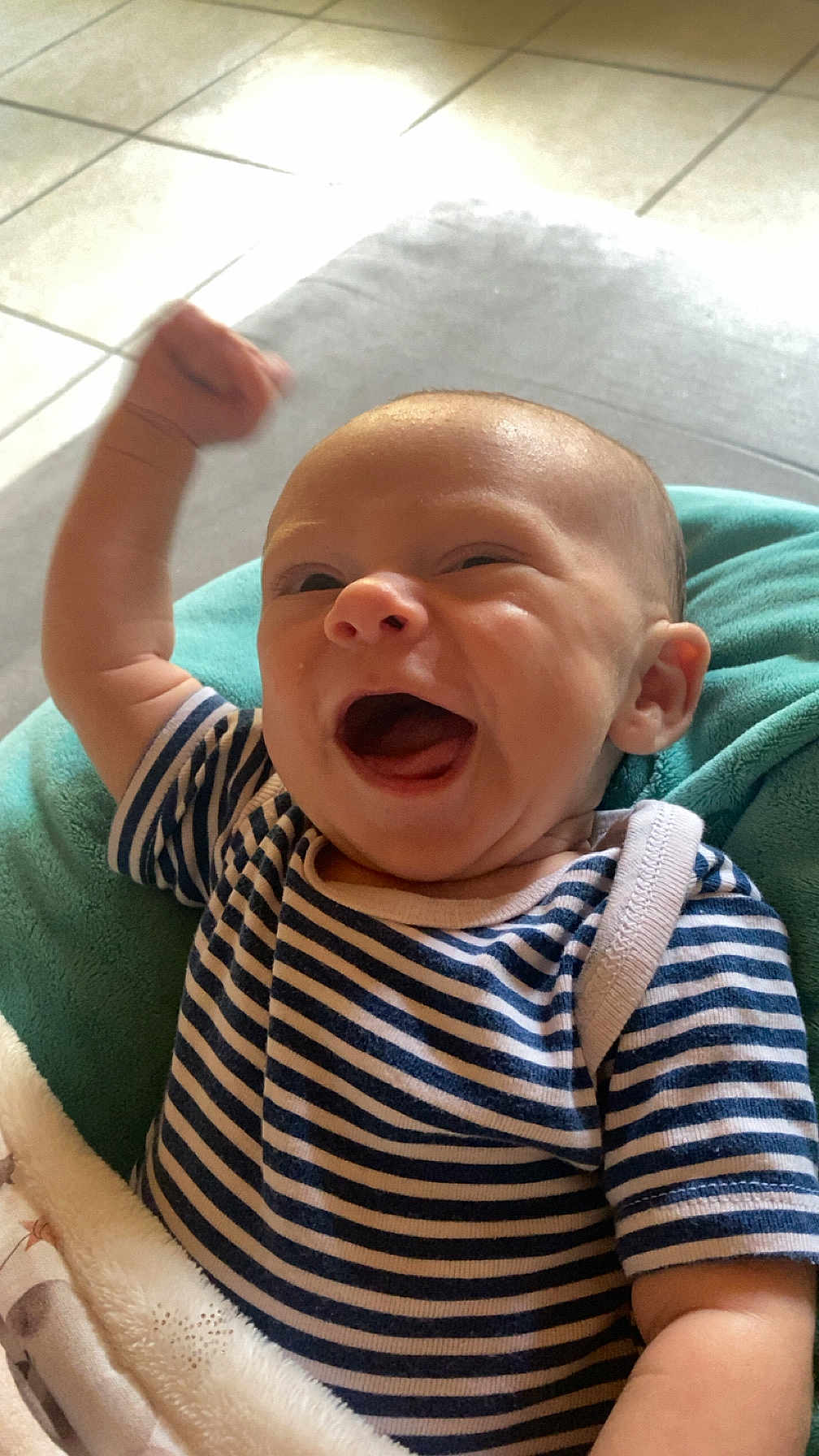 Azyo participe au concours pour gagner de l'argent avec cette photo : baby, infant, smiling, happy, striped_clothing, onesie, blanket, indoor, tiled_floor, cheerful, raised_arm, cute, child, portrait, infant_clothing, fist_pump, young_child, candid, person, joy