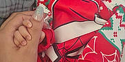 Damien Vincent is registered to the contest to win money with this photo: baby, infant, sleeping, hand, holding, finger, red_clothing, spider_man, onesie, festive, blanket, cozy, soft_focus, cute, child, newborn, person, indoor, portrait, closeup