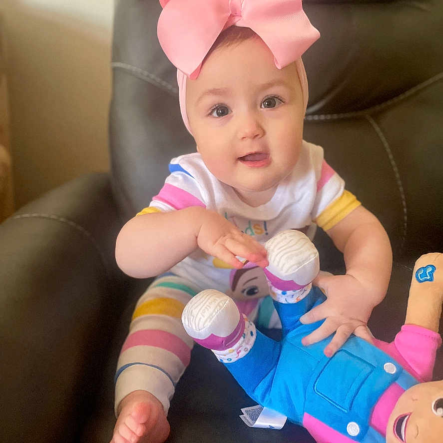 Emma is registered to the contest to win money with this photo: baby, bodypart, bonnet, cap, clothing, costume, couch, cushion, face, finger, furniture, hand, hat, head, homedecor, person, photography, portrait, sitting, toy