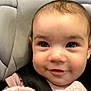baby, smiling, blanket, car_seat, face, child, indoor, close_up, video_call, technology, wood_floor, adult, seatbelt, comfort, portrait, happy, person, candid, cute, cozy
