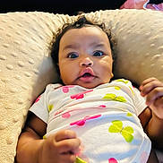 Jessie joined the competition — help win amazing prizes! baby, infant, child, curly_hair, onesie, butterfly_print, cushion, soft_texture, lying_down, wide_eyes, cute, hand, fist, indoor, portrait, closeup, expression, skin, clothing, newborn