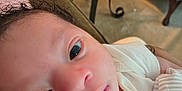 Tevon Xavier Brown joined the competition — help win amazing prizes! baby, close_up, face, infant, person, curly_hair, white_clothing, mittens, indoor, couch, table, glass_table, carpet, furniture, home, resting, newborn, skin, portrait, young_child
