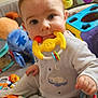 Timeo a rejoint le concours — aidez-le/la à gagner de superbes lots ! baby, infant, teething_toy, colorful_toys, stuffed_animal, playpen, onesie, close_up, indoor, sitting, chubby_cheeks, big_eyes, portrait, hand, chewing_toy, nursery, playtime, soft_toys, bright_colors, family_photo