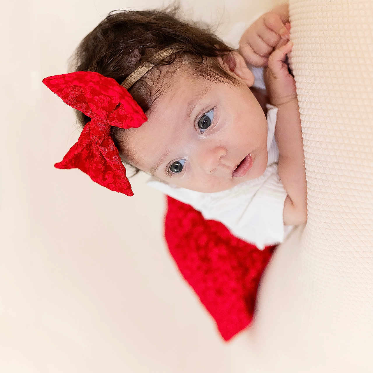 Kataleya participe au concours pour gagner de l'argent avec cette photo : baby, child, closeup, curly_hair, cute, expression, face, hands, headband, indoors, infant, laying_down, person, portrait, red_bow, red_skirt, skin, soft_lighting, white_clothing, young