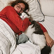 Chucky a rejoint le concours — aidez-le/la à gagner de superbes lots ! person, cat, bed, blanket, pillow, glasses, sleeping, cozy, indoor, resting, fur, white, black, red_sweater, wooden_headboard, comfort, cuddling, relaxation, home, soft