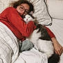 person, cat, bed, blanket, pillow, glasses, sleeping, cozy, indoor, resting, fur, white, black, red_sweater, wooden_headboard, comfort, cuddling, relaxation, home, soft
