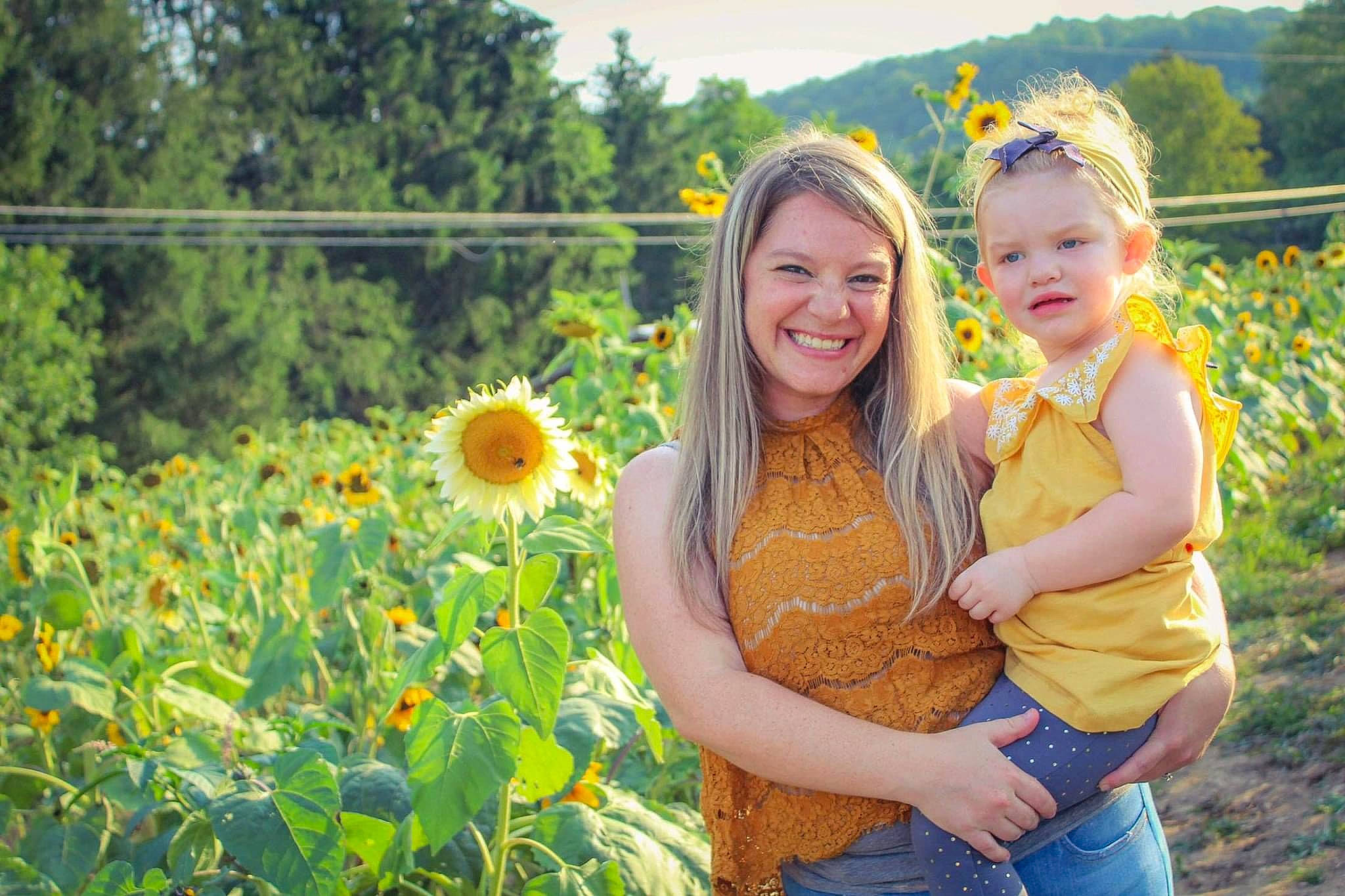 Jayleigh joined the competition — help win amazing prizes! botany, face, flower, gesture, grass, grassland, happy, joy, landscape, leisure, meadow, people_in_nature, person, petal, plant, prairie, rural_area, smile, summer, toddler