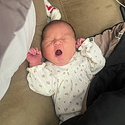 Camila is registered to the contest to win money with this photo: baby, infant, yawn, sweater, floral_pattern, couch, blanket, sleepy, cozy, indoor, person, child, newborn, cute, relaxing, soft_lighting, face, hand, portrait, home