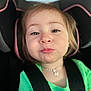 toddler, child, car_seat, green_shirt, necklace, crumbs, close_up, face, seatbelt, straps, hair, expression, portrait, indoors, cute, young_child, person, casual_clothing, car_interior, safety